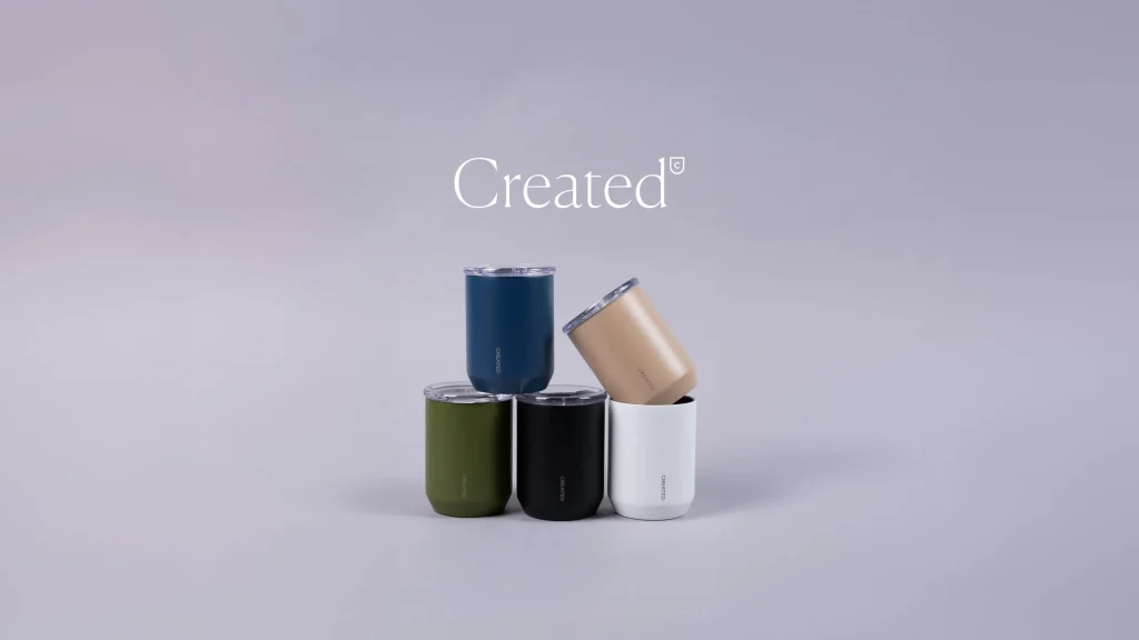 A stack of Created Co. tumblers in four stylish colors: blue, green, tan, and white.