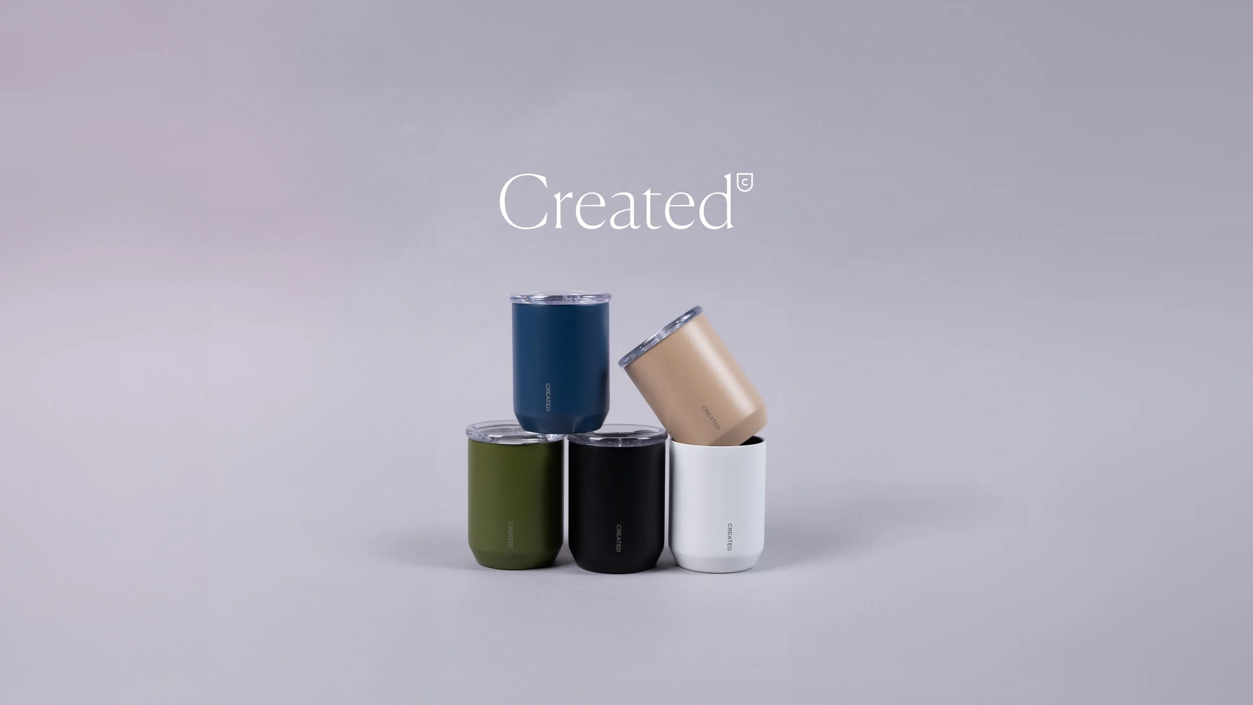 A stack of Created Co. tumblers in four stylish colors: blue, green, tan, and white.